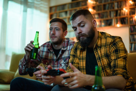 Two best friends playing video games while relaxing at home on the couch and drinking beer