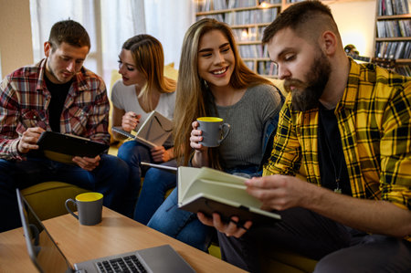 Group of students studying at home for their exam while drinking coffee and using a laptopの写真素材
