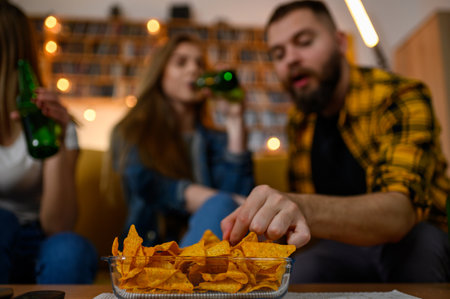 Bowl full of nachos on a table on a house party while the people are blurry in the background