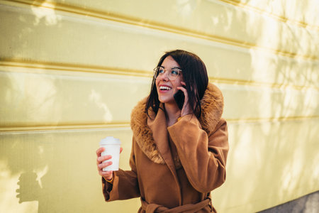 Cropped shot of a young woman talking on her cellphone and drinking coffeeの写真素材