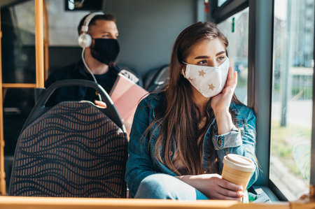 Young woman wearing protective mask while riding a bus during covid19 world pandemicの写真素材