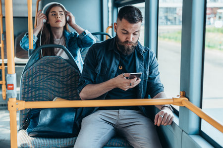 Young beautiful passengers using smartphones while riding the bus during the day in the city