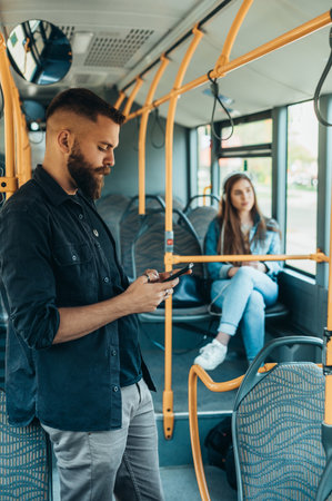Young handsome man riding a bus while using a smartphone and looking through the windowの写真素材