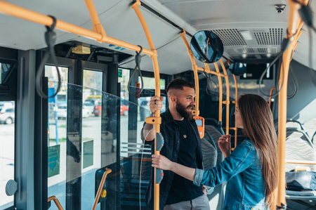 Young attractive couple standing in a moving bus and talking while flirtingの写真素材