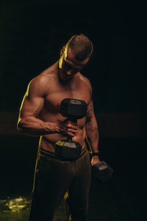 Handsome shirtless man lifting dumbbell in the gymの写真素材
