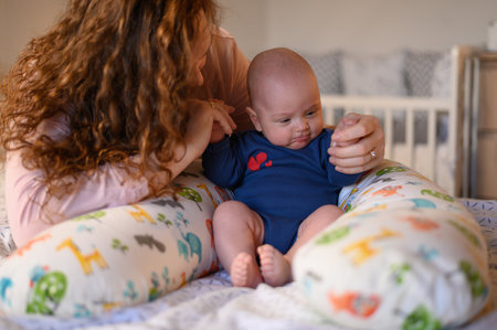 Mother bonding with her baby boy while helping him to learn how to sit