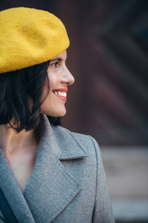 Close shot of a portrait of a young woman wearing yellow beret and a gray coatの写真素材