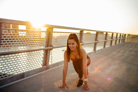 Shot of a beautiful young attractive woman getting ready to start running on the bridgeの写真素材