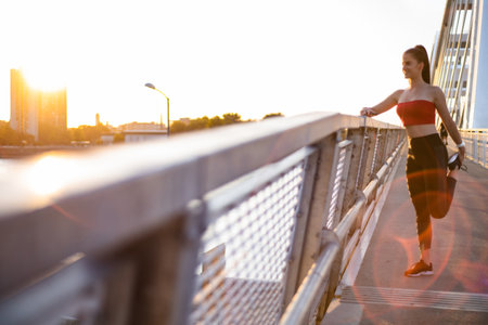 Shot of a attractive female jogger catching a brake after running on a bridgeの写真素材
