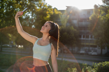 Shot of a young woman taking selfies during a workout in the cityの写真素材
