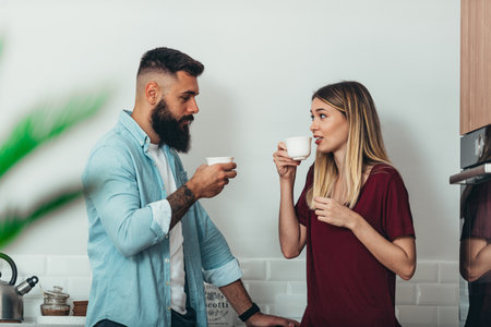Shot of a young couple having coffee and a chat in the kitchen at homeの写真素材