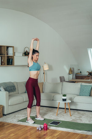Shot of an attractive young woman working out at home while using a digital tabletの写真素材