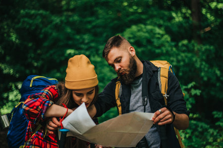 A couple of hikers using smartphone for orientation while spending time in nature and wearing backpacks with a camping gearの写真素材