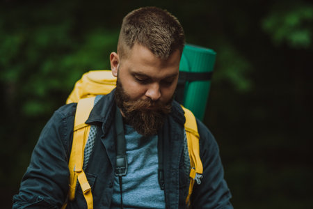 A hiker man walking in the forest and wearing backpack with camping gear