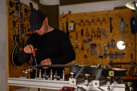 Black electrical guitar in repair service shop with a guitar luthier which fixes and tightens itの写真素材