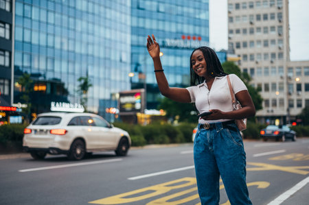 Beautiful african american woman using smartphone while calling a cab on a city streetの写真素材