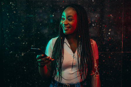 Cheerful african american woman using smartphone while in a subway metro platformの写真素材
