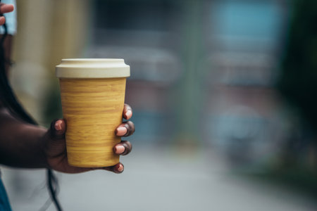 Hand of an african american woman holding a reusable coffee cup made of an eco materialの写真素材