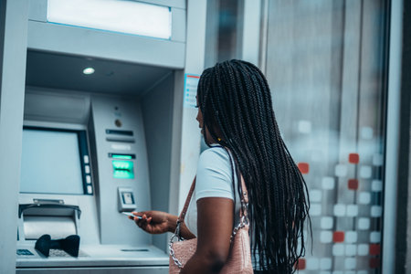 Young african american woman using credit card and an atm machine while out in the cityの写真素材