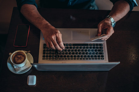 Hands of a senior hispanic cuban men using a laptop and a credit card while online shopping