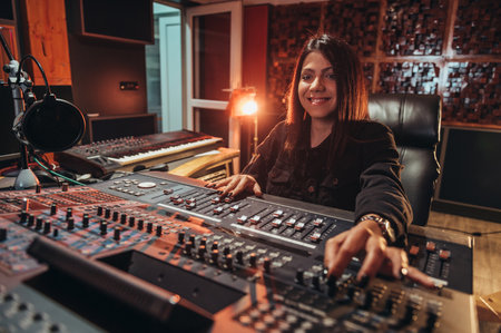 Young woman music producer working on a mixing soundboard while in her studioの写真素材