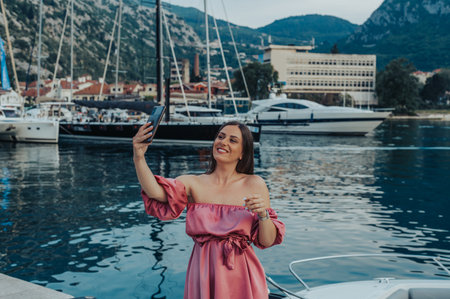 Beautiful young woman taking selfie with smartphone while walking through the portの写真素材