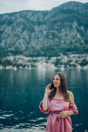 Beautiful young woman using smartphone while walking on the city streets on the coast