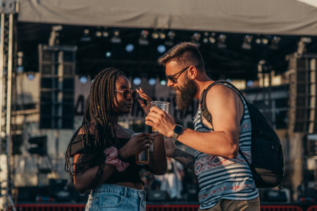 Romantic couple drinking beer and having fun at music festivalの写真素材