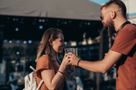 Romantic couple drinking beer and having fun at music festivalの写真素材