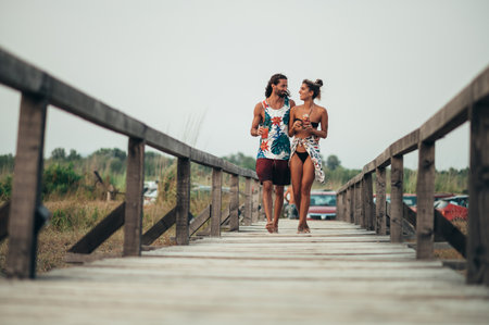 Attractive young couple with alcohol cocktails walking on the beachの写真素材
