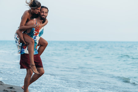 Attractive young couple with alcohol cocktails walking on the beachの写真素材