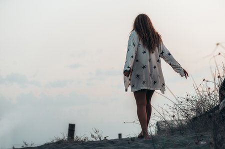 Beautiful girl walking on the beach during sunsetの写真素材