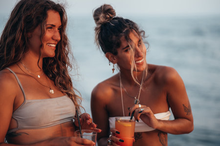 Attractive friends enjoying vacation together on the beach and drinking cocktailsの写真素材