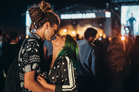 Young happy couple kissing at music festival in the night. Young people in love. Love, music and...