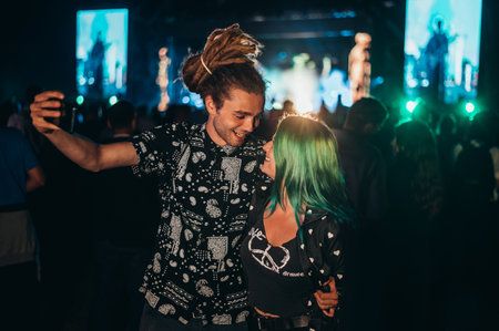 Teenage couple at summer music festival taking selfie with a smartphone while dancing in front of stage. New music entertainment trends. People in love.の写真素材