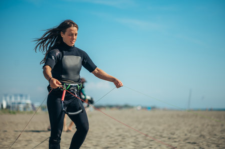 Young woman extreme sport enthusiasts using flying lines and a control bar while assembling kitesurfing equipment. Preparation before kiting.の写真素材