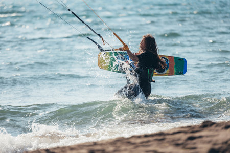 Young sporty woman going into the water ready to go kitesurfing while holding a kiteboard.の写真素材