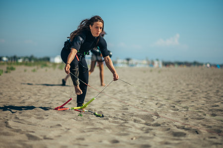 Young woman extreme sport enthusiasts using flying lines and a control bar while assembling kitesurfing equipment. Preparation before kiting.の写真素材