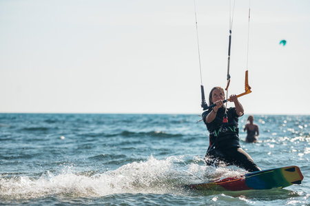 Young sporty woman on a kiteboard kitesurfing on the clear waves of the ocean and having fun. Woman kitesurfer. Active water recreational sport.の写真素材