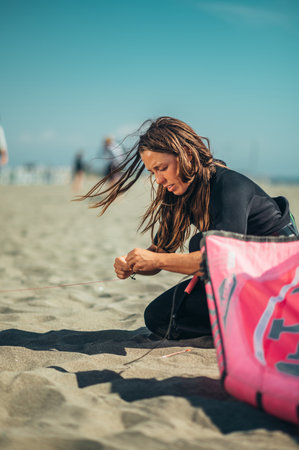 Young woman extreme sport enthusiasts using flying lines and a control bar while assembling kitesurfing equipment. Preparation before kiting.の写真素材
