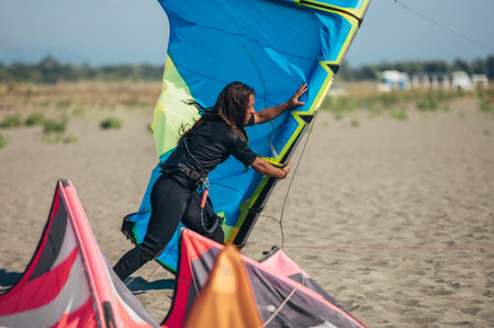 Woman holding a kite while still on the beach and preparing to go kitesurfing. Preparation before...