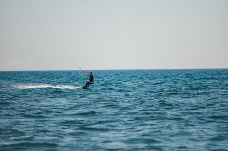 Young sporty woman on a kiteboard kitesurfing on the clear waves of the ocean and having fun. Woman...