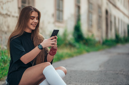 Young woman sitting on her longobard on the road and using a smartphoneの写真素材