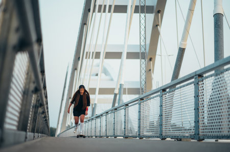 Young woman riding her longboard on the bridgeの写真素材