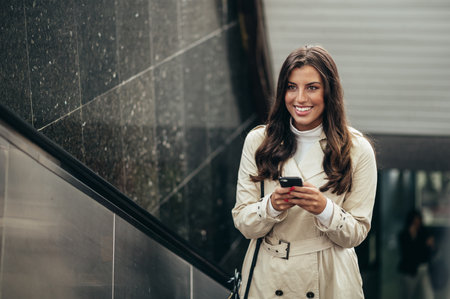 Beautiful young woman using a smartphone and riding the escalator in the subwayの写真素材