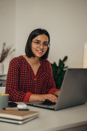 Beautiful woman using a laptop while managing her business and working remotely from homeの写真素材