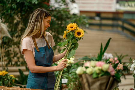 Florist woman working in a flower shop and standing at a counter and making a bouquet of fresh flowersの写真素材