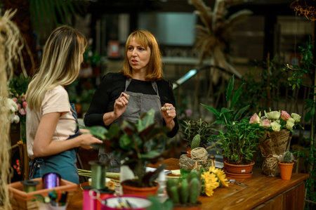 Experienced woman florist helping young employee how their business works and how to deal with...