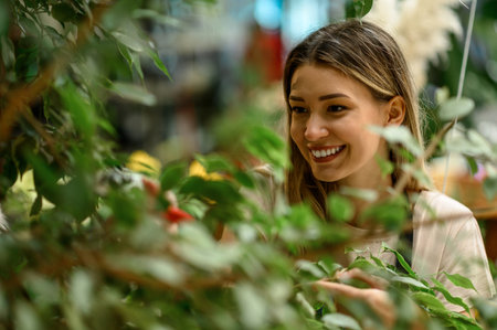 Beautiful young florist taking care of a plant while using pruning shears and working in a flower shopの写真素材