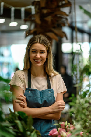 Portrait of beautiful florist working in flower shop while smiling and looking at a camera